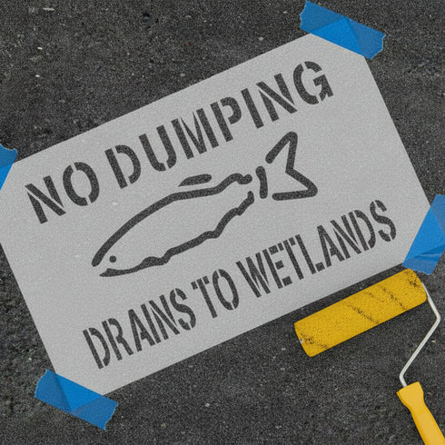 Draints to Wetlands stencil being painted onto asphalt.