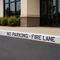 No parking fire lane sign on a street in front of a building.
