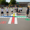 Children playing hopscotch on a playground with colorful grid markings.