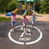 Children playing on the Hop Fitness Circle on a playground pavement sruface.