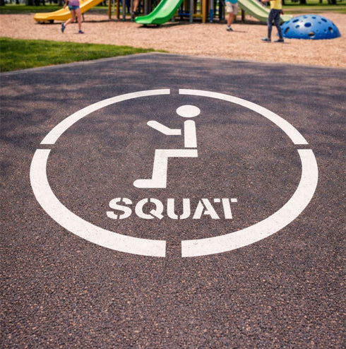 Squat symbol on a playground surface with children playing in the background
