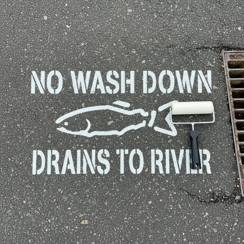 Stenciled warning on a sidewalk about not washing down drains to a river
