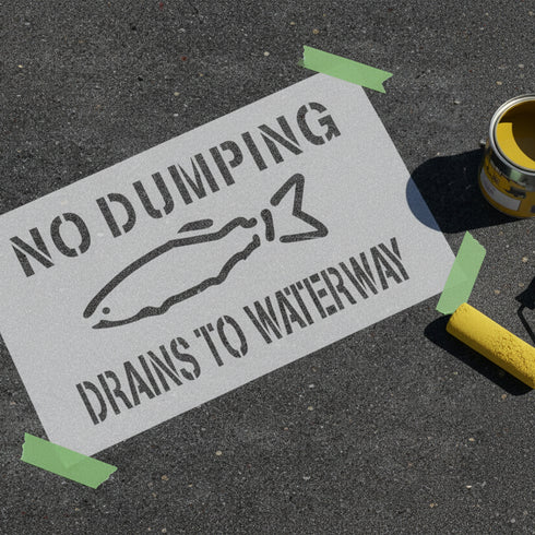 Sign with 'No Dumping Drains to Waterway' text and a fish illustration on a dark surface.