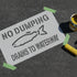 Sign with 'No Dumping Drains to Waterway' text and a fish illustration on a dark surface.