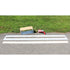 Multiple width parking line stencils displayed on a paved surface with a stencil holder and spray paint tool nearby.
