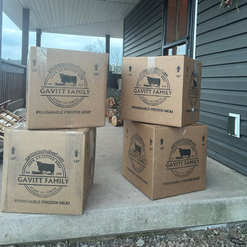 Four boxes labeled 'Gavitt Family' on a porch, containing perishable frozen meat.
