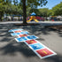 Colorful hopscotch grid on a playground surface with a playground in the background.