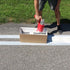 Person using a spray can with parking line stencils on a road, demonstrating easy line application.
