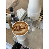 Cup of coffee with artistic foam design and the name 'Dait' on a cafe counter.