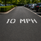 10 MPH speed limit sign on a road with parked cars in the background
