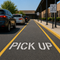 Pick Up Stencil applied to the parking lot of a elementary school pick up line.