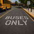 Yellow school bus on a road with 'Buses Only' markings and signs.