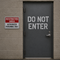 Door with 'Do Not Enter' sign and nearby 'Restricted Area' sign on a brick wall.