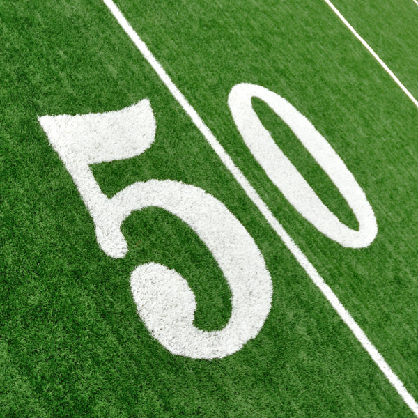 Close-up of a stencil number '50' on a green football field surface, representing the product's use in marking sports fields.