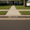 Stenciled 'M GO BLUE' on a residential curb with a sidewalk in front of a house.