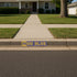 Stenciled 'M GO BLUE' on a residential curb with a sidewalk in front of a house.
