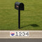 Black mailbox on a grassy area with a street address sign featuring the Chicago Cubs logo.