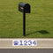 Black mailbox on a grassy area with a street address sign featuring wildcat paw prints and numbers.