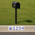 Black mailbox on a grassy area with a street address sign featuring wildcat paw prints and numbers.