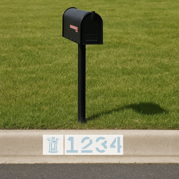 Black mailbox on a grassy area with a street address sign in the foreground.