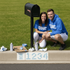 Two people in blue UNC shirts sitting next to a mailbox with spray paint and supplies on the ground.
