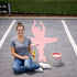 High School senior sitting on a parking lot with a pink ballerina painted onto it.