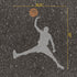 Silhouette of a basketball player with a ball stenciled on an asphalt surface, showing dimensions.