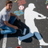Student painting a mural on a parking lot with baseball player stencil