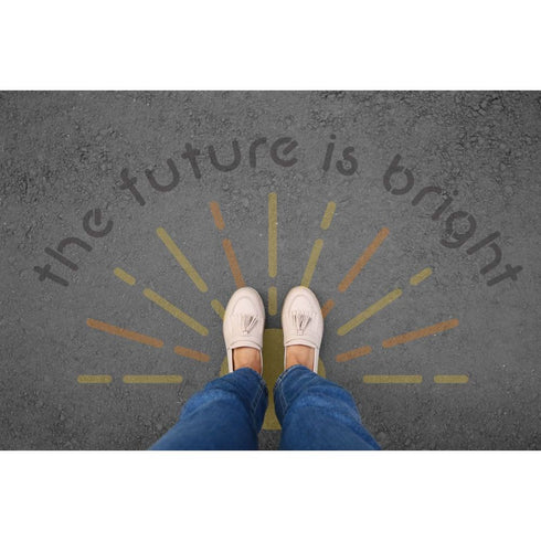 Person standing on pavement that has been stenciled with 'The Future is Bright' text.