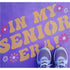 Person standing on pavement that has been stenciled with 'In My Senior Era!' text.