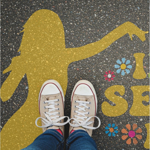 Person standing on pavement that has been stenciled with a Taylor Swift silhouette.