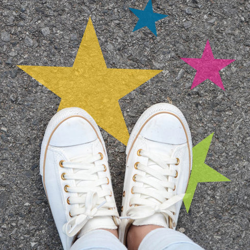 Person standing on pavement that has been stenciled with Stars.