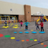 Children playing on a playground with colorful markings in front of a school building.