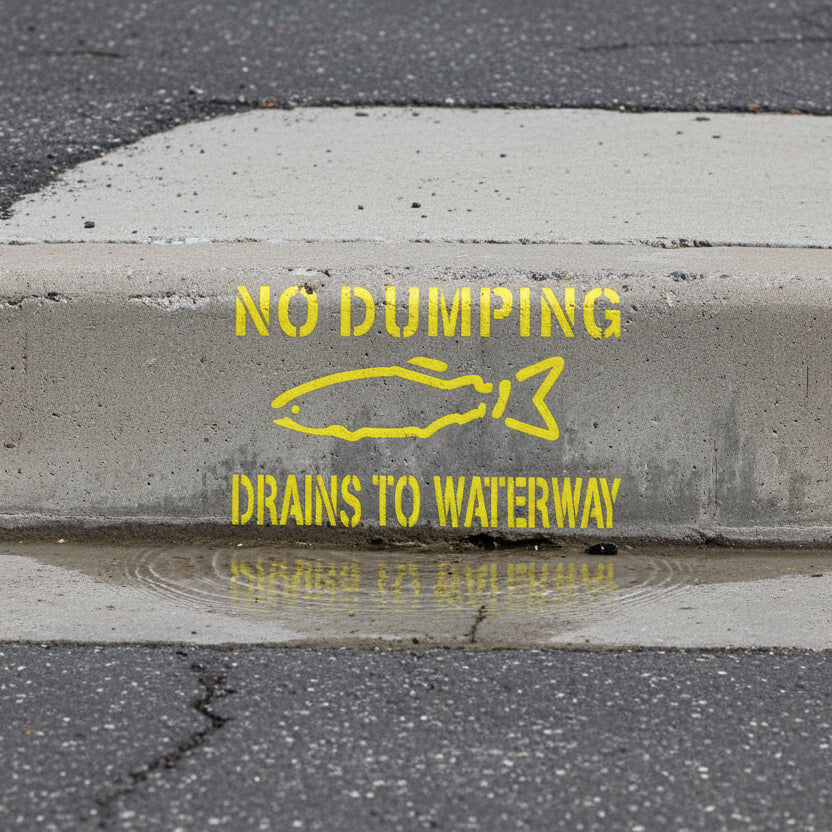 Yellow 'No Dumping Drains to Waterway' sign with a fish outline on a white background